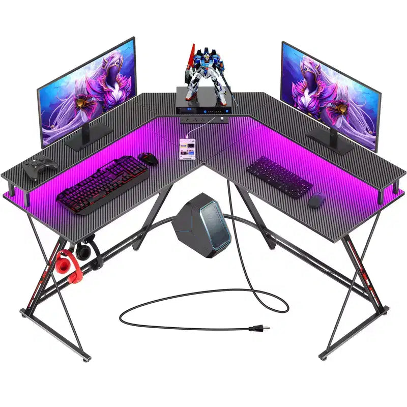 Scrivania a L Greenstell 128 cm – Superficie in fibra di carbonio con luce LED e prese di corrente, tavolo da gaming con supporto per monitor e gancio per cuffie